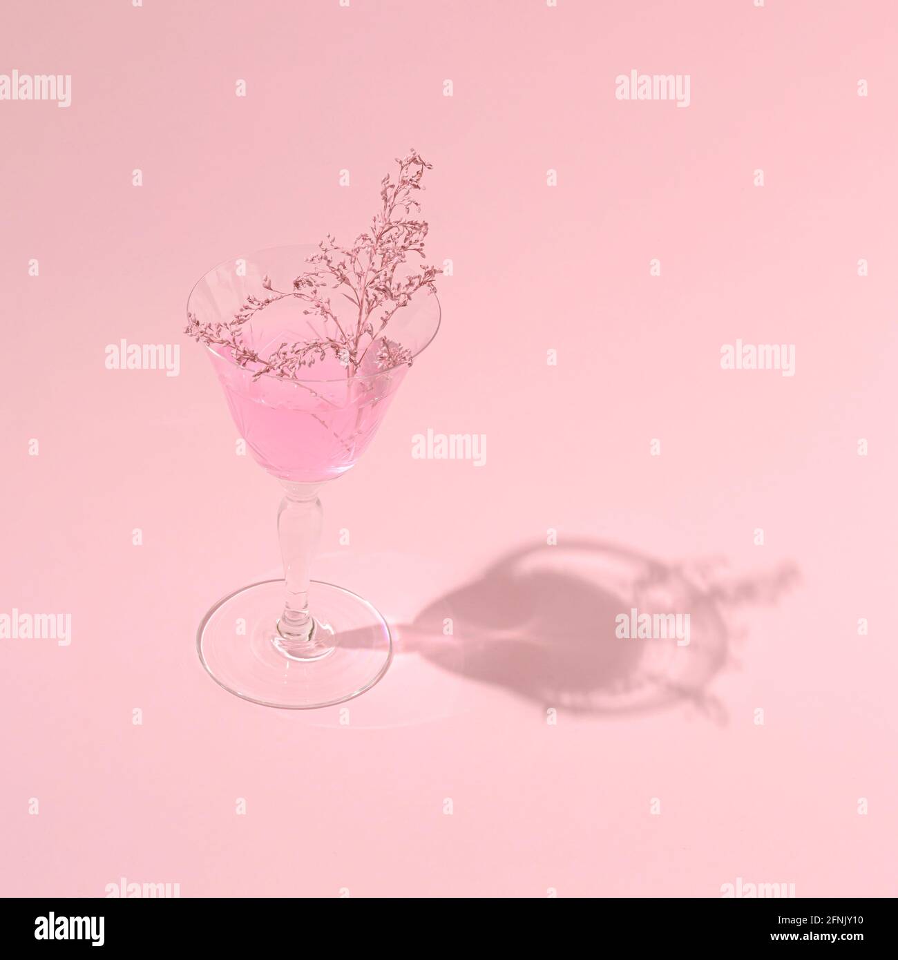 Pink drink with added pink herb in a glass on a light background. Monochromatic colors. Summer party concept Stock Photo
