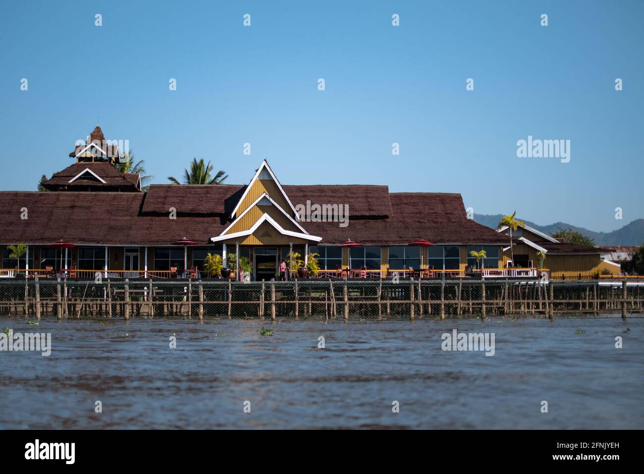 A big yellow elevated building on the riverside of the canals at Inle Lake, Nyaung Shwe, Shan state, Myanmar Stock Photo