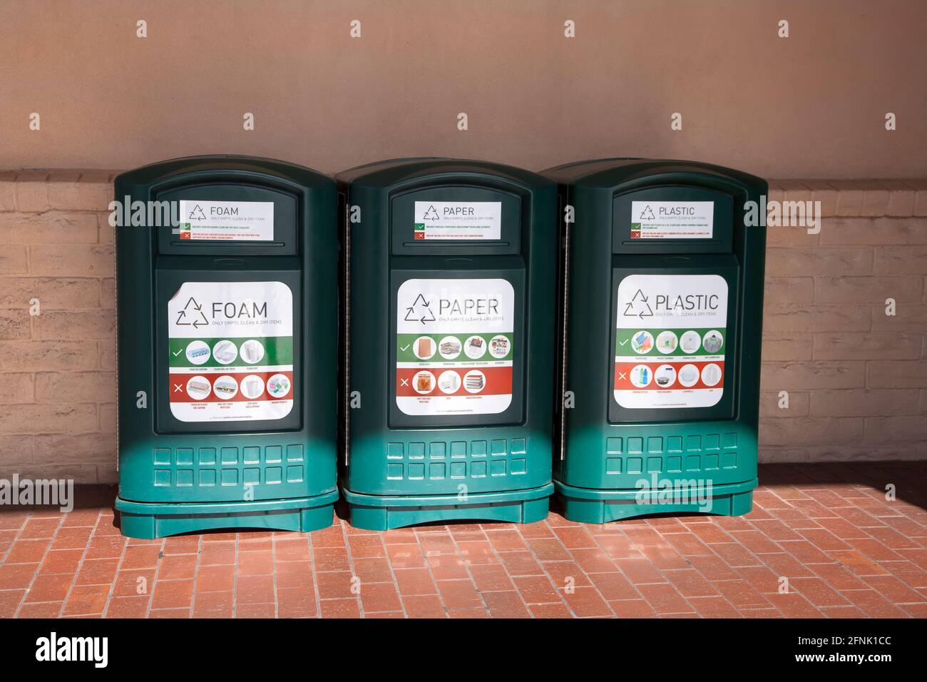 Three types of recycling bins (foam, paper, and plastic) outside of a