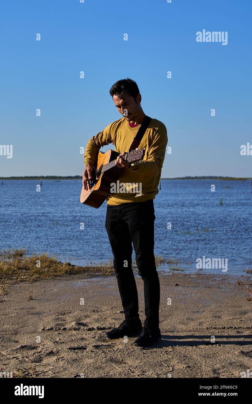 young man playing guitar in wild pl Stock Photo