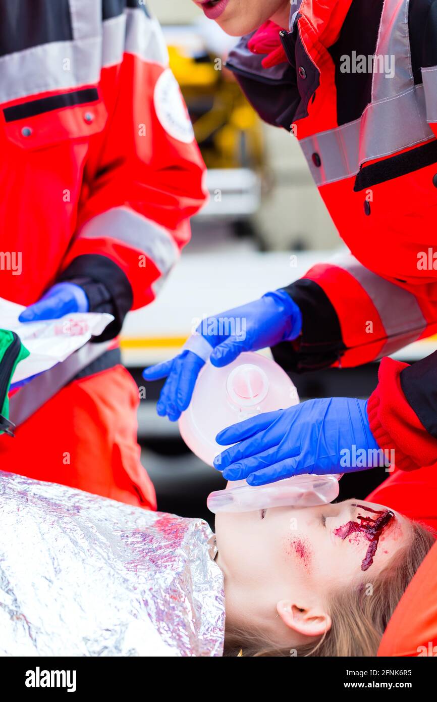 Emergency doctor and nurse or ambulance team giving oxygen to accident victim Stock Photo