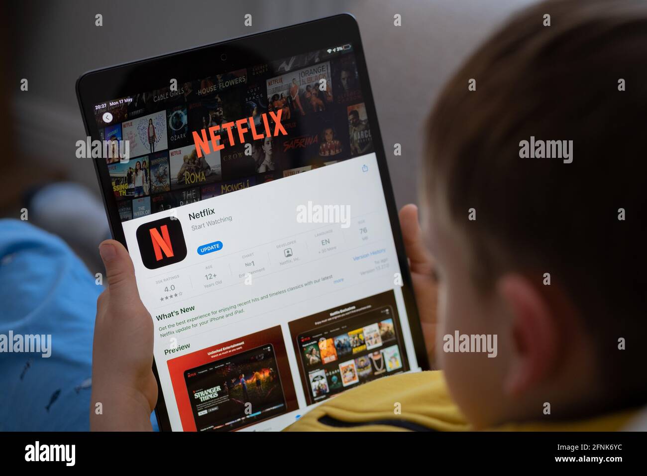 NETFLIX app seen on the screen of ipad which is in the hands of  unrecognisable child. Concept. Stafford, United Kingdom, May 18, 2021. Stock Photo