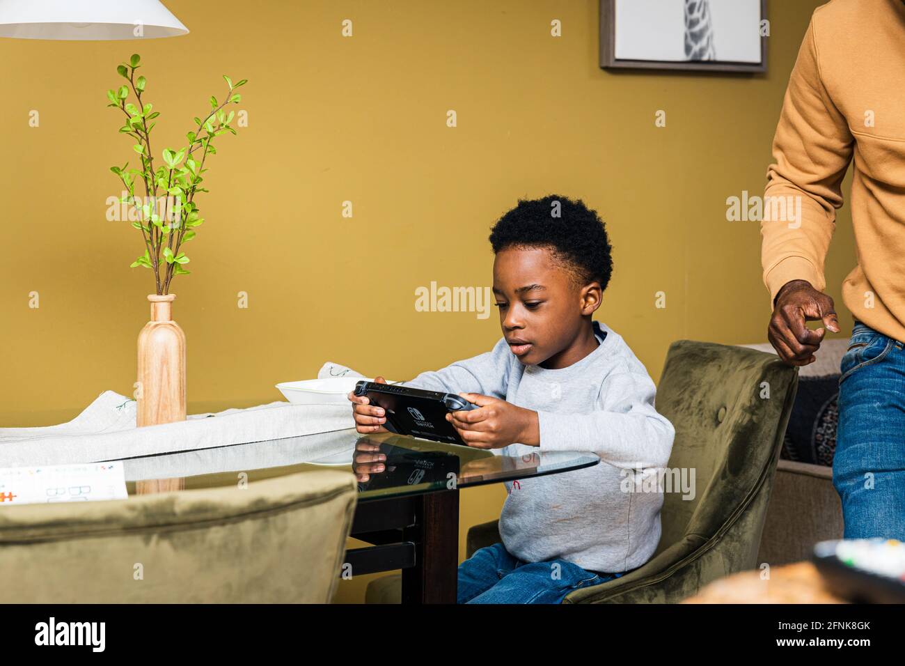 Boy using smart phone while sitting on chair at table Stock Photo