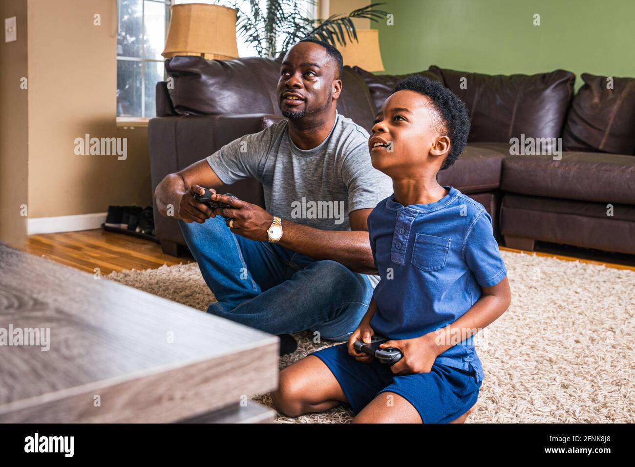 Father and son playing video game in living room at home Stock Photo