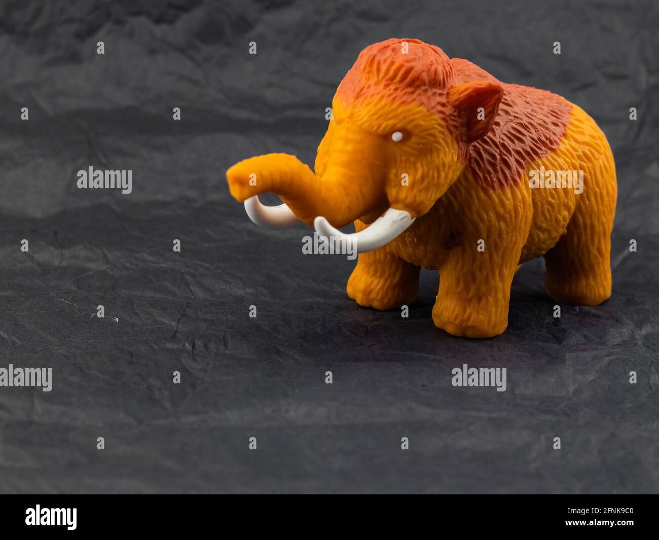 small toy mammoth on dark background Stock Photo