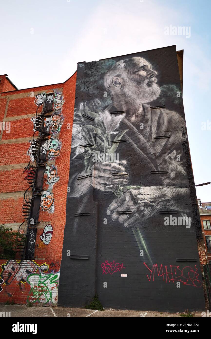 A huge street mural of an older man holding a bunch of flowers on the rear fire escape side of a tall building in Antwerp, Belgium Stock Photo