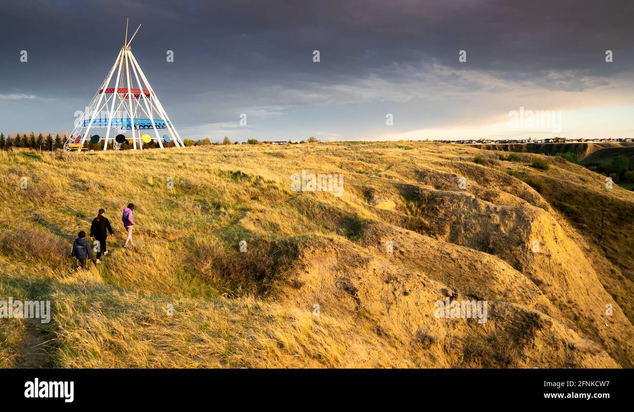 Medicine Hat Alberta Canada, May 13 2021: A family walks outdoors along a hiking trail in Seven Persons Coulee by the Sammis Tepee at sunset. Stock Photo