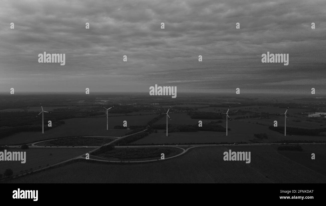 Grayscale shot of wind turbines along the road under a cloudy sky Stock ...