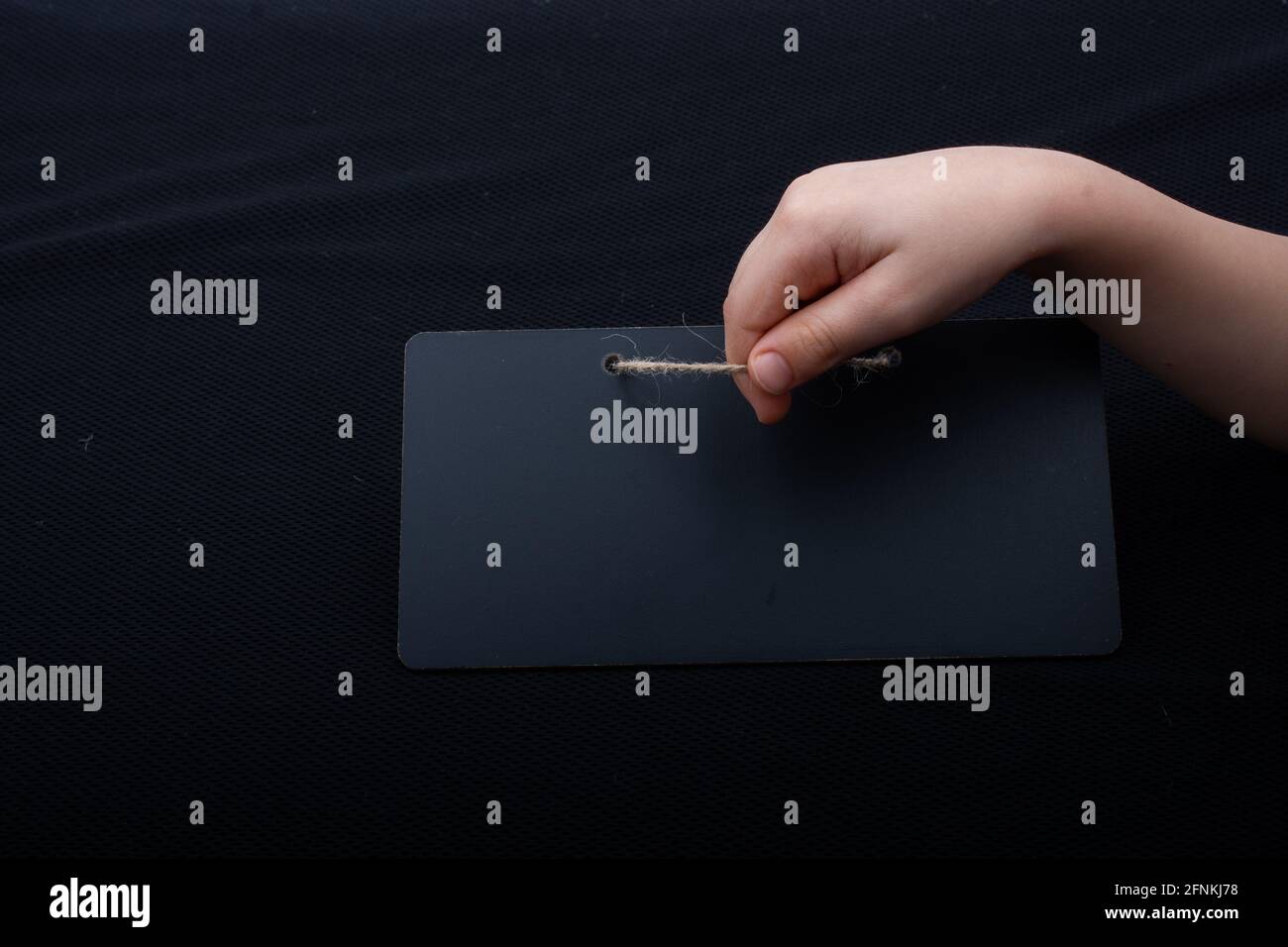Rectangular shaped black notice board in hand on black background Stock Photo