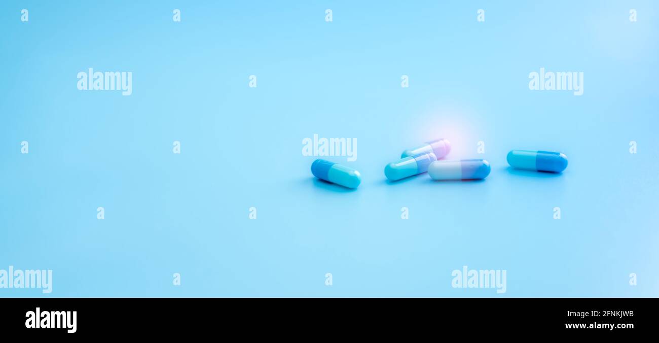 Blue capsule pills on blue background. Pharmacy shop banner. Healthcare and medicine. Pharmaceutical industry. Drug research and development for treat Stock Photo