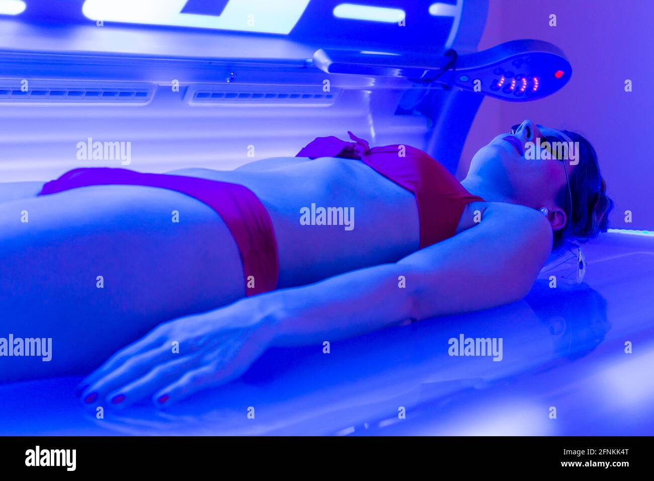 Woman in bikini tanning in wellness spa solarium Stock Photo