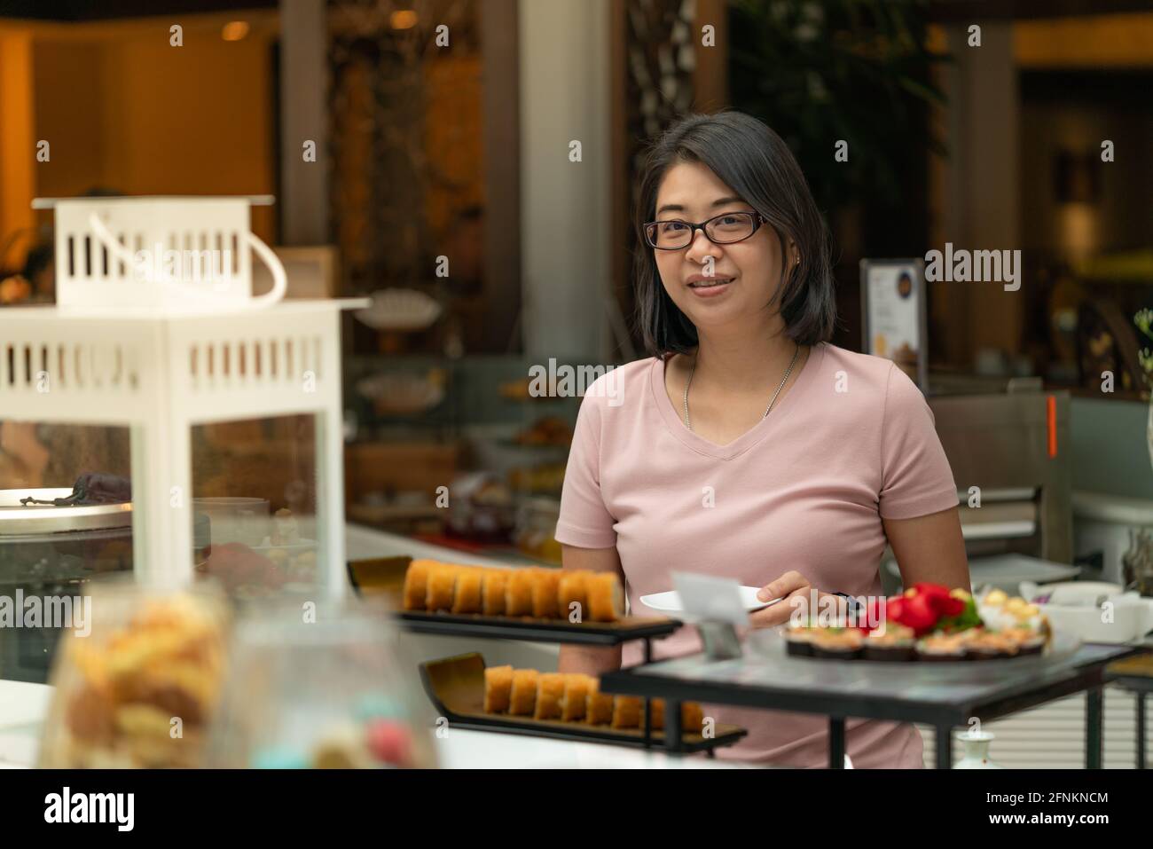 Portrait Asian woman selecting food at food bar, buffet breakfast in a restaurant. Stock Photo