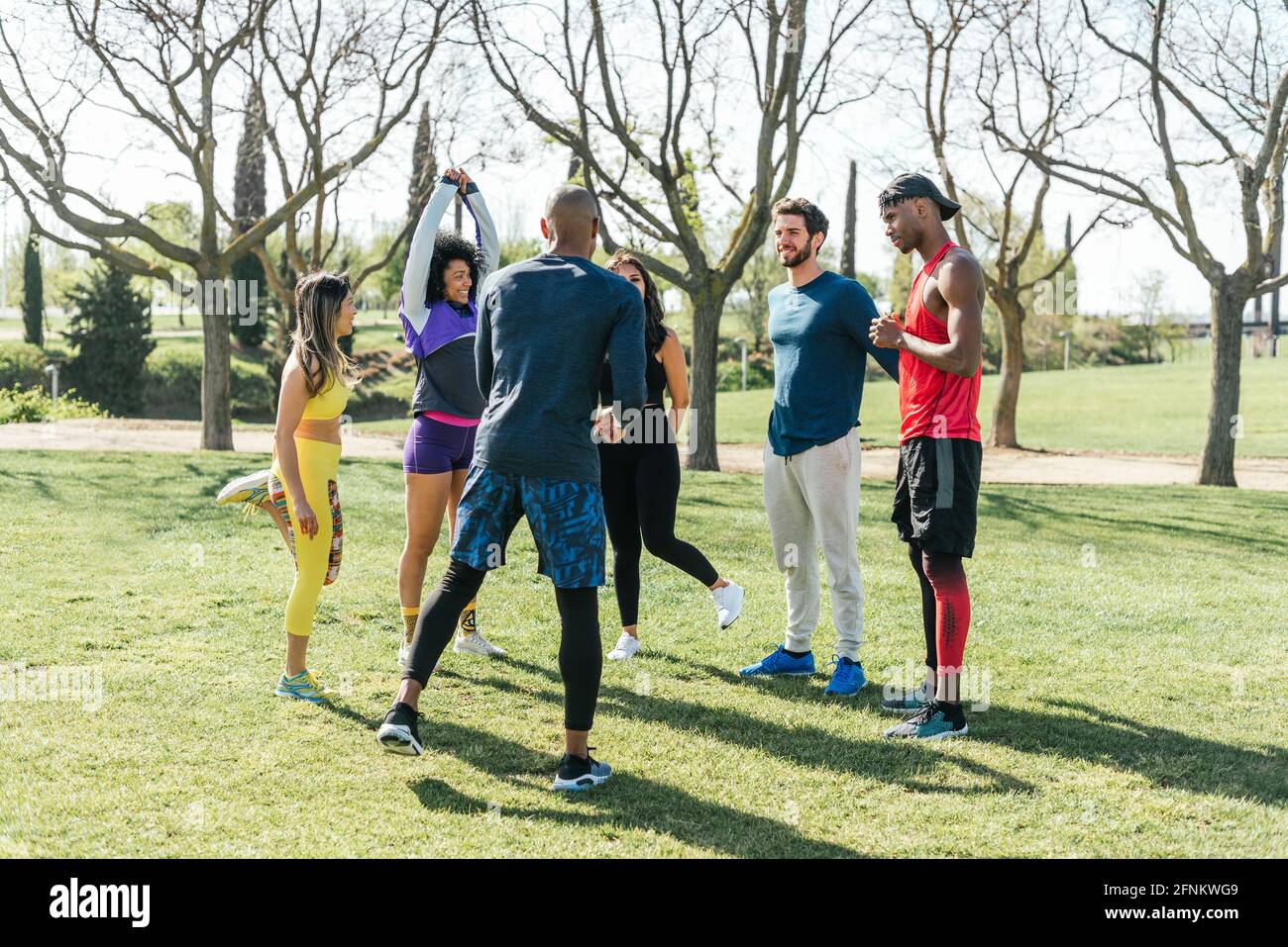 Group of friendly runners talking in a park before training. Stock Photo