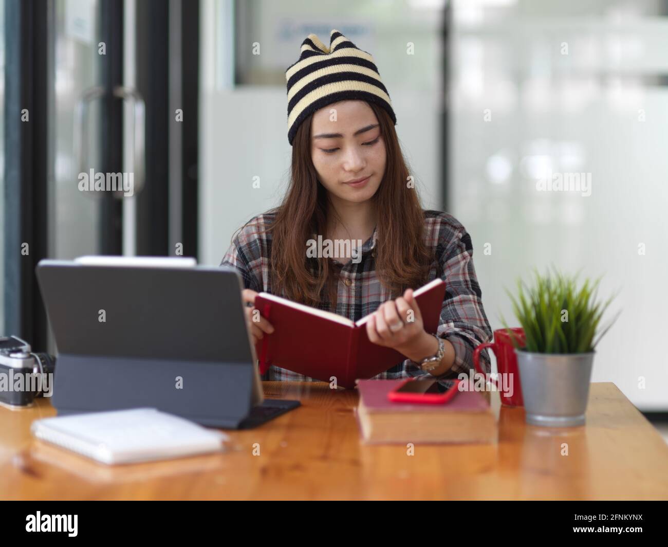 Portrait of female teenager doing assignment with book and tablet in ...