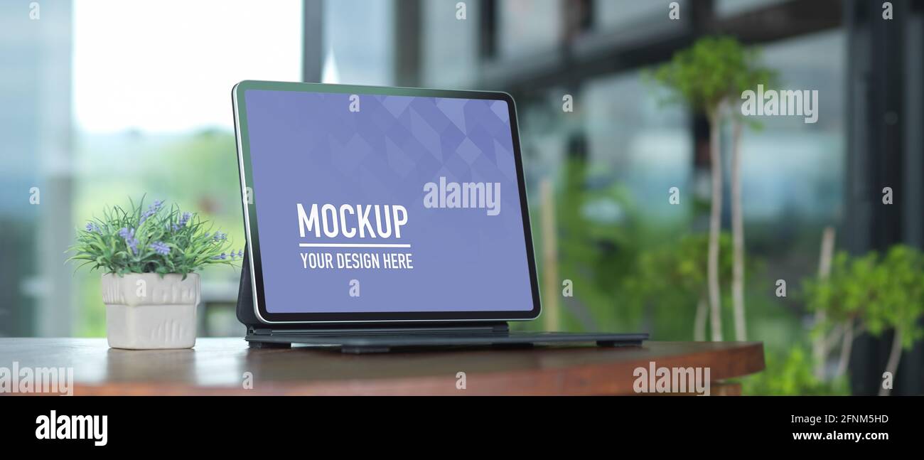 Cropped shot of portable workspace with laptop and plant pot on wooden table, clipping path Stock Photo