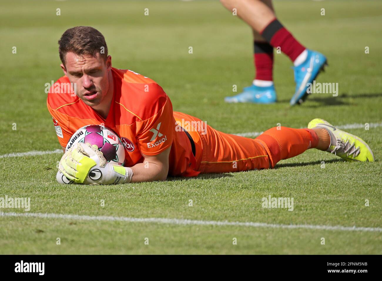 Nuremberg, Germany. 16th May, 2021. Football: 2. Bundesliga, 1. FC Nürnberg - VfL Bochum, 33. matchday at Max-Morlock-Stadion. Nuremberg goalkeeper Christian Mathenia lies on the pitch with the ball. Credit: Daniel Karmann/dpa - IMPORTANT NOTE: In accordance with the regulations of the DFL Deutsche Fußball Liga and/or the DFB Deutscher Fußball-Bund, it is prohibited to use or have used photographs taken in the stadium and/or of the match in the form of sequence pictures and/or video-like photo series./dpa/Alamy Live News Stock Photo