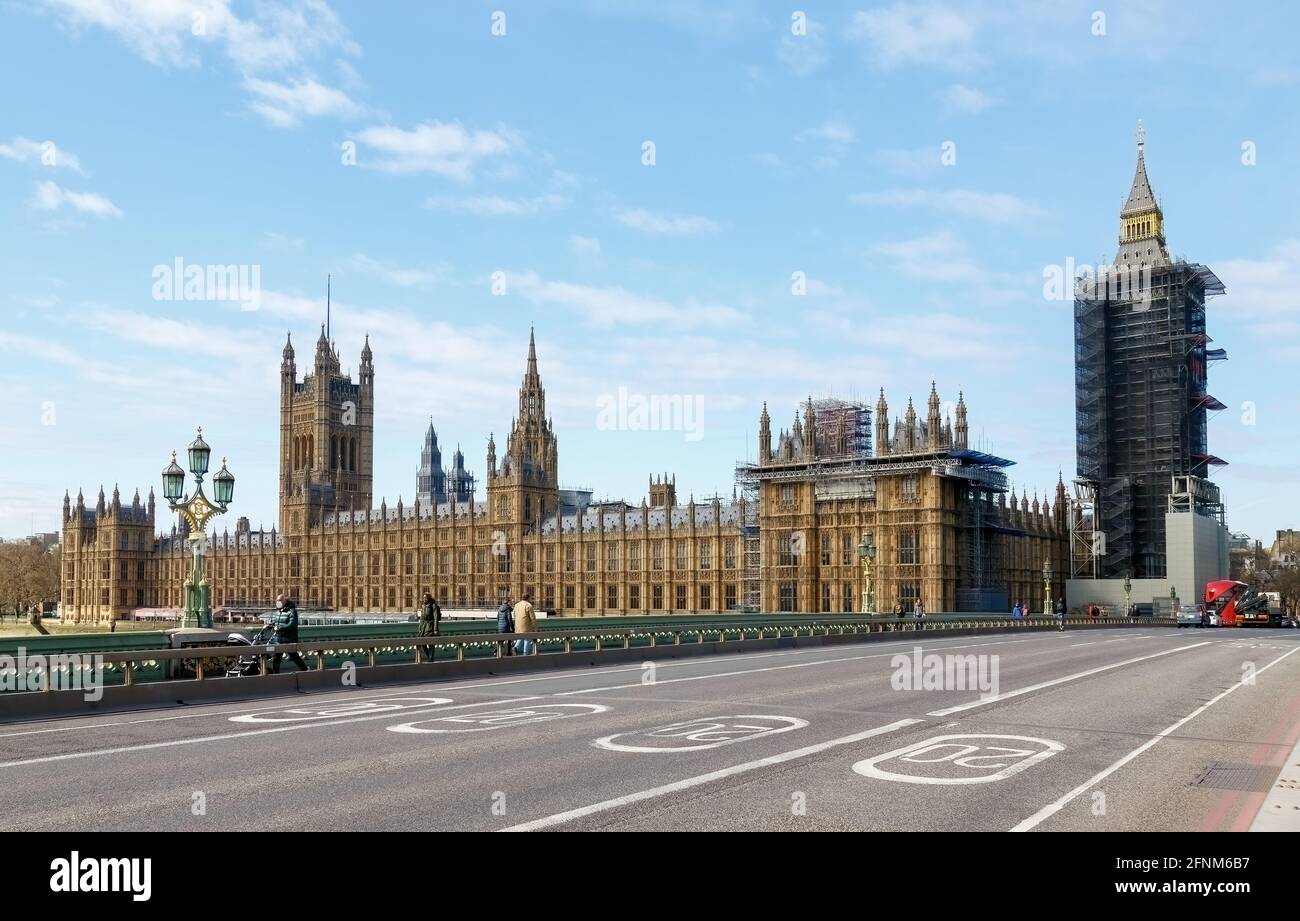 Houses of Parliament from Westminster Bridge with people wearing face masks are socially distanced apart and vehicles at the end of the bridge. Stock Photo