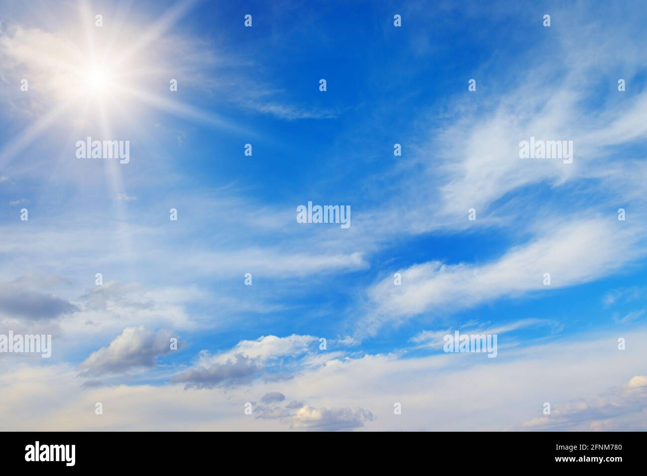 Bright sun and white clouds in blue sky Stock Photo