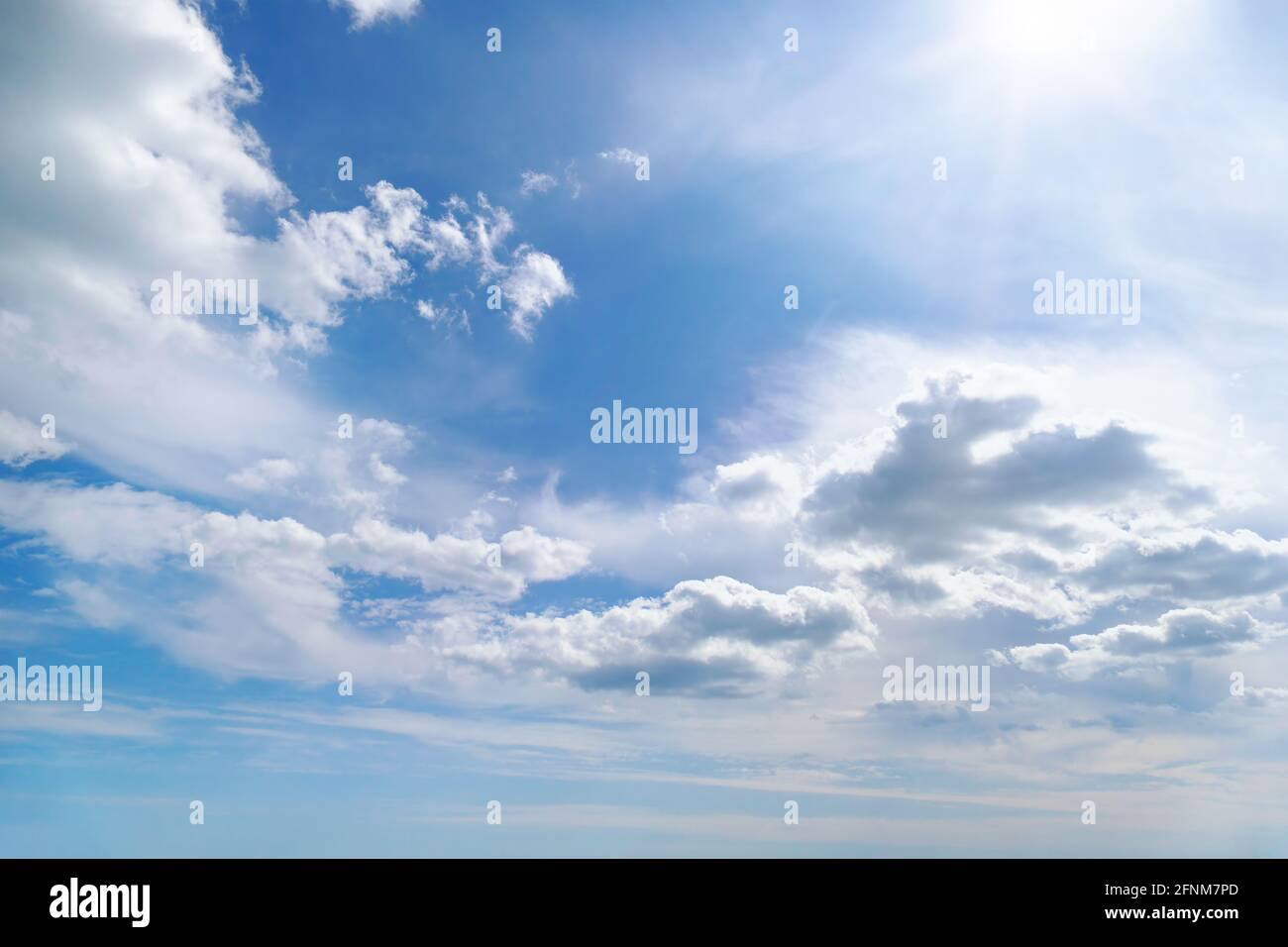 Bright summer sun on blue sky with white fluffy clouds. Stock Photo