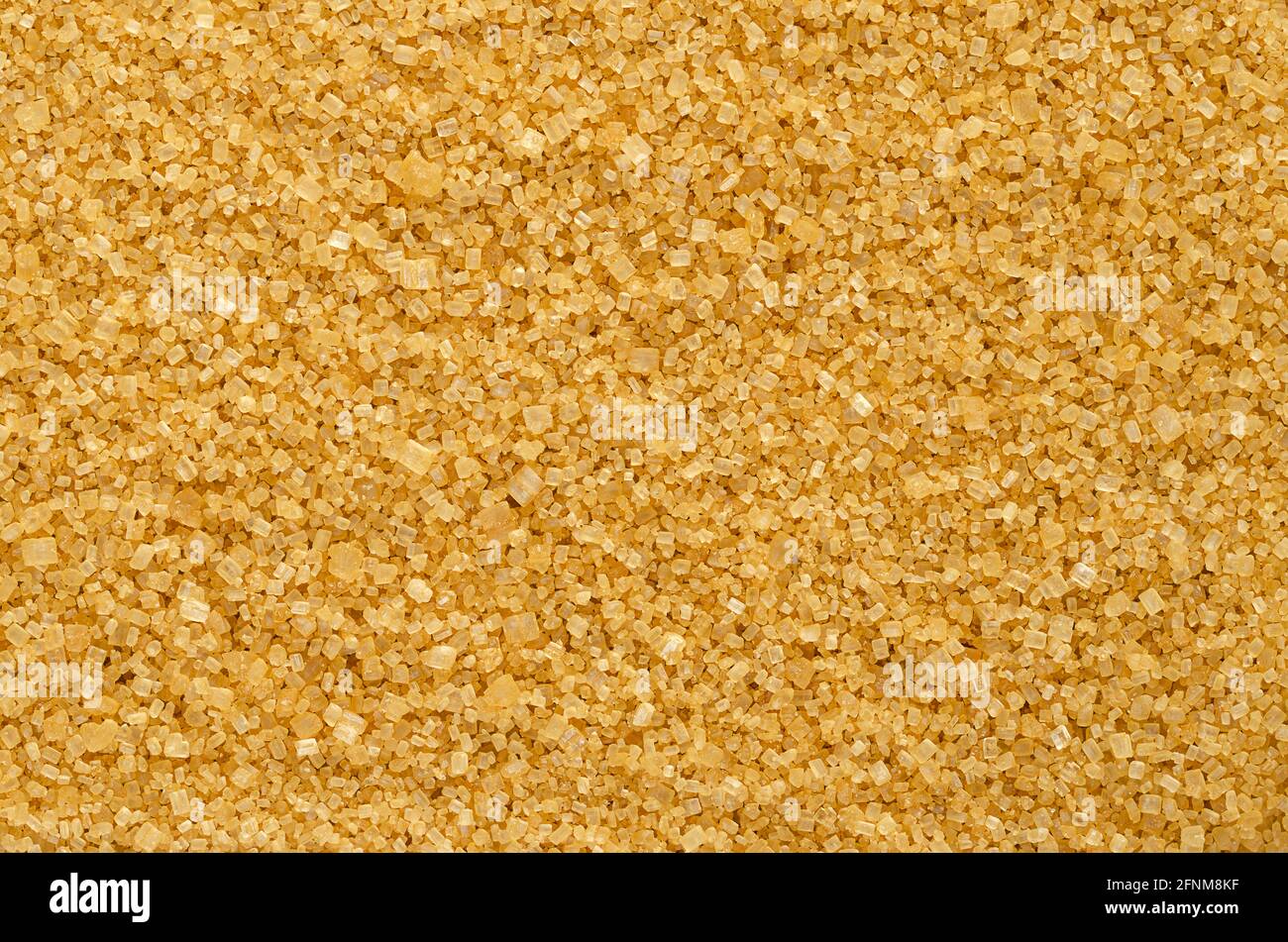Brown demerara sugar, background, from above. Coarse, crystalline, natural and raw sugar, a sucrose sugar with distinctive yellow-brown color. Stock Photo