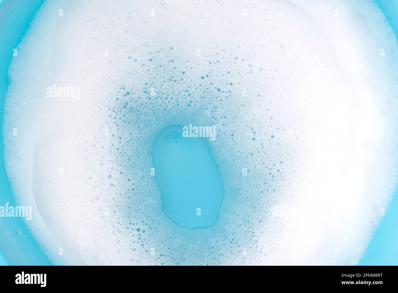 Foam on surface of water in blue plastic basin. Foam as texture or background. Stock Photo