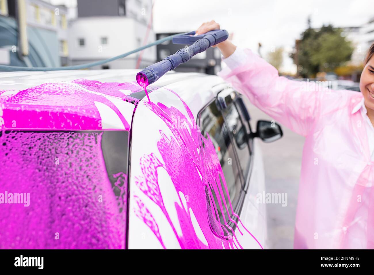 Caucasian woman washing car at self-serve car wash with pink foam, stock photo Stock Photo