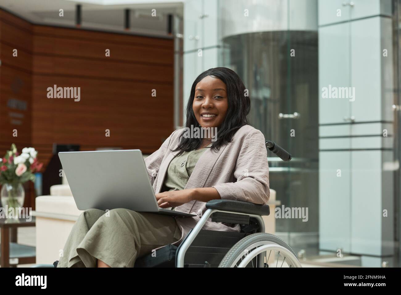 Portrait of African disabled woman smiling at camera while sitting in ...