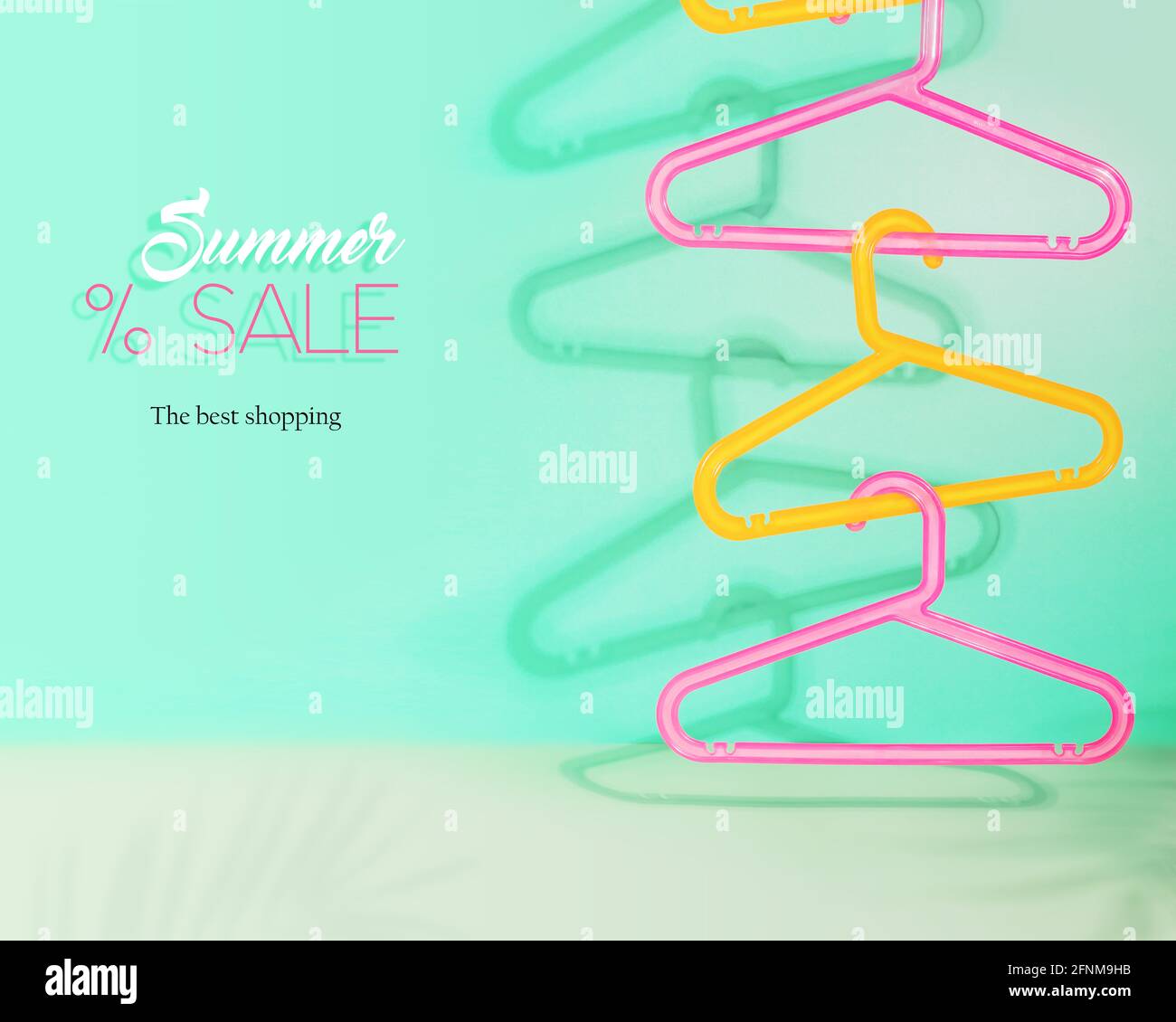 Horizontal summer sale composition with colored plastic hangers hung on top of each other on a light blue background with shadows and text Stock Photo