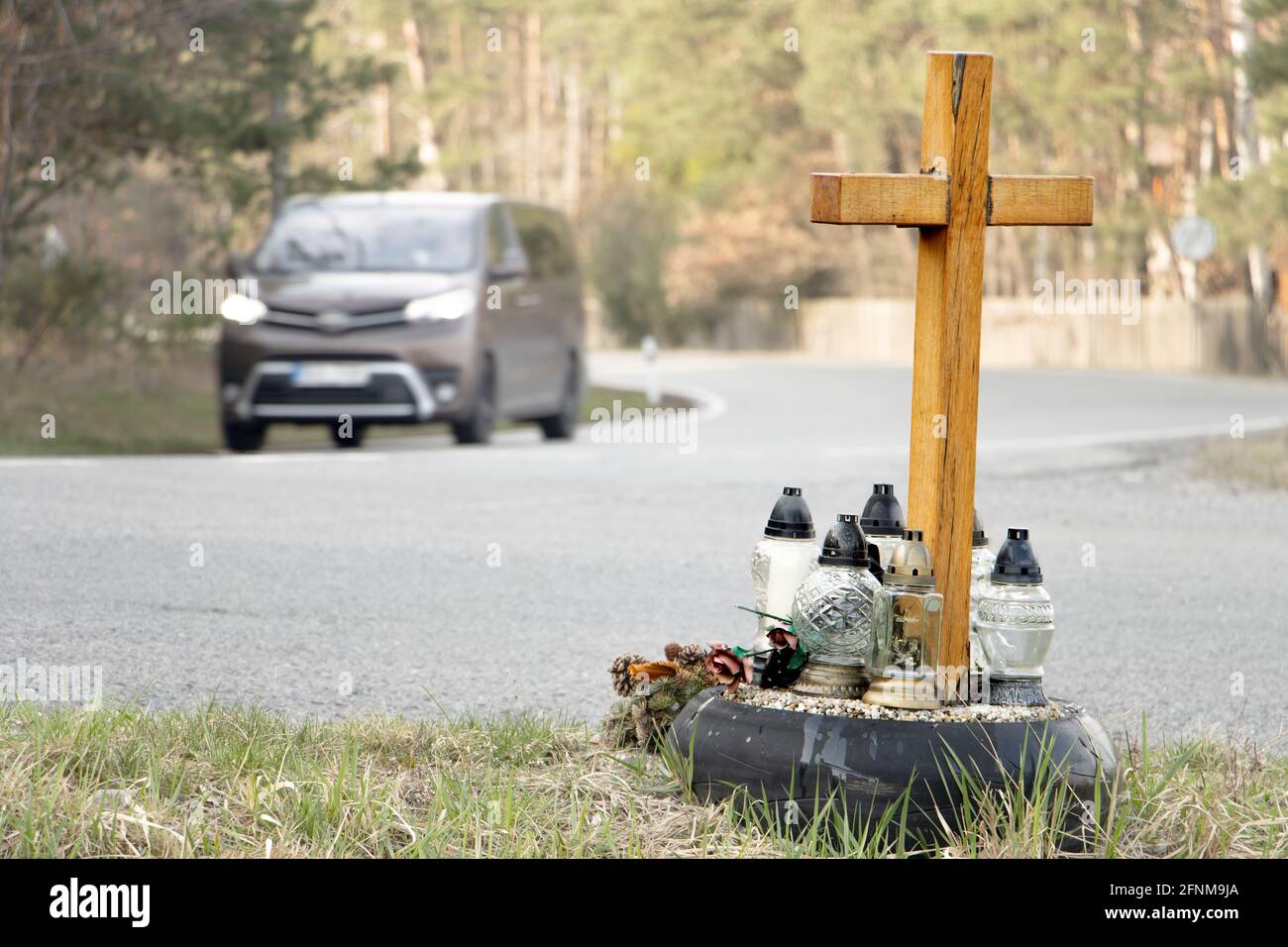 A roadside memorial cross with a candles commemorating the tragic death, on a background ride blurred car. Stock Photo