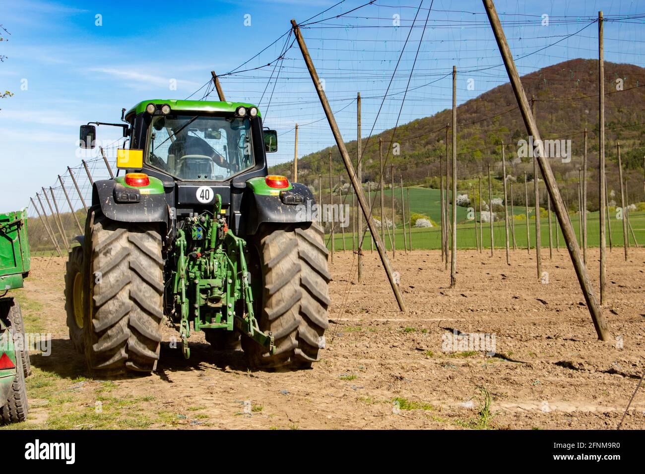 A tractor ride on way beside a hop-garden during spring work Stock ...