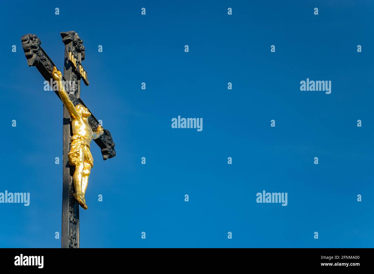 A iron cross with the crucified Jesus Christ on a background of blue sky Stock Photo