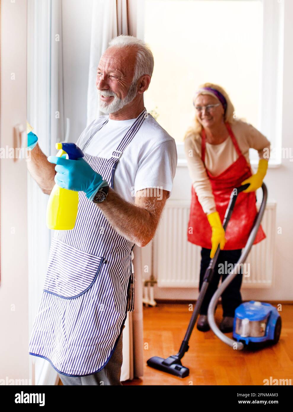 Senior man cleaning windows and woman vacuuming at home Stock Photo Alamy