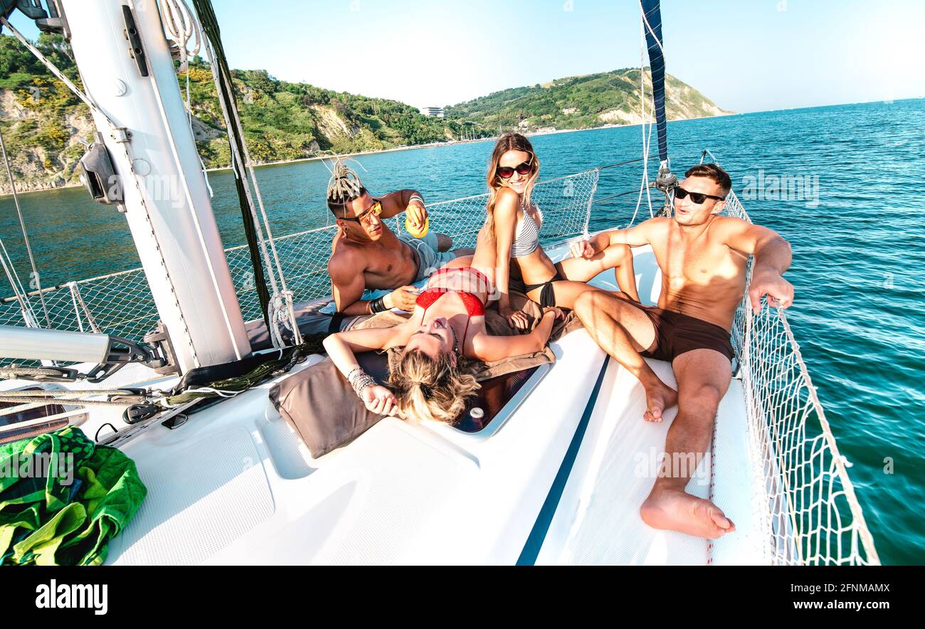 Young rich friends chilling on sailboat at sea trip - Guys and girls having summer fun together at sail boat party day - Luxury excursion concept Stock Photo