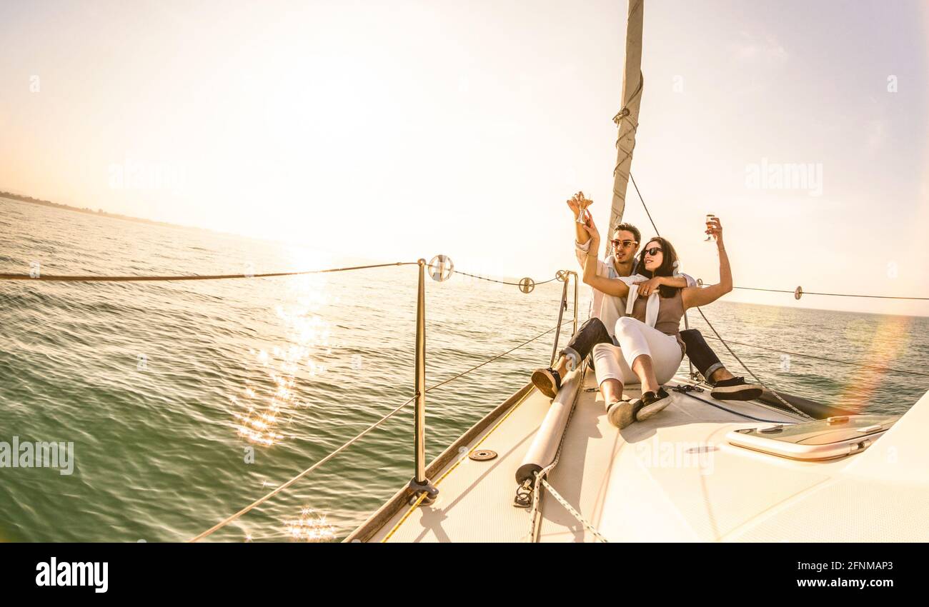 Young lovers couple on sail boat with champagne at sunset - Exclusive luxury concept with rich millennial people lifestyle on tour around the world Stock Photo