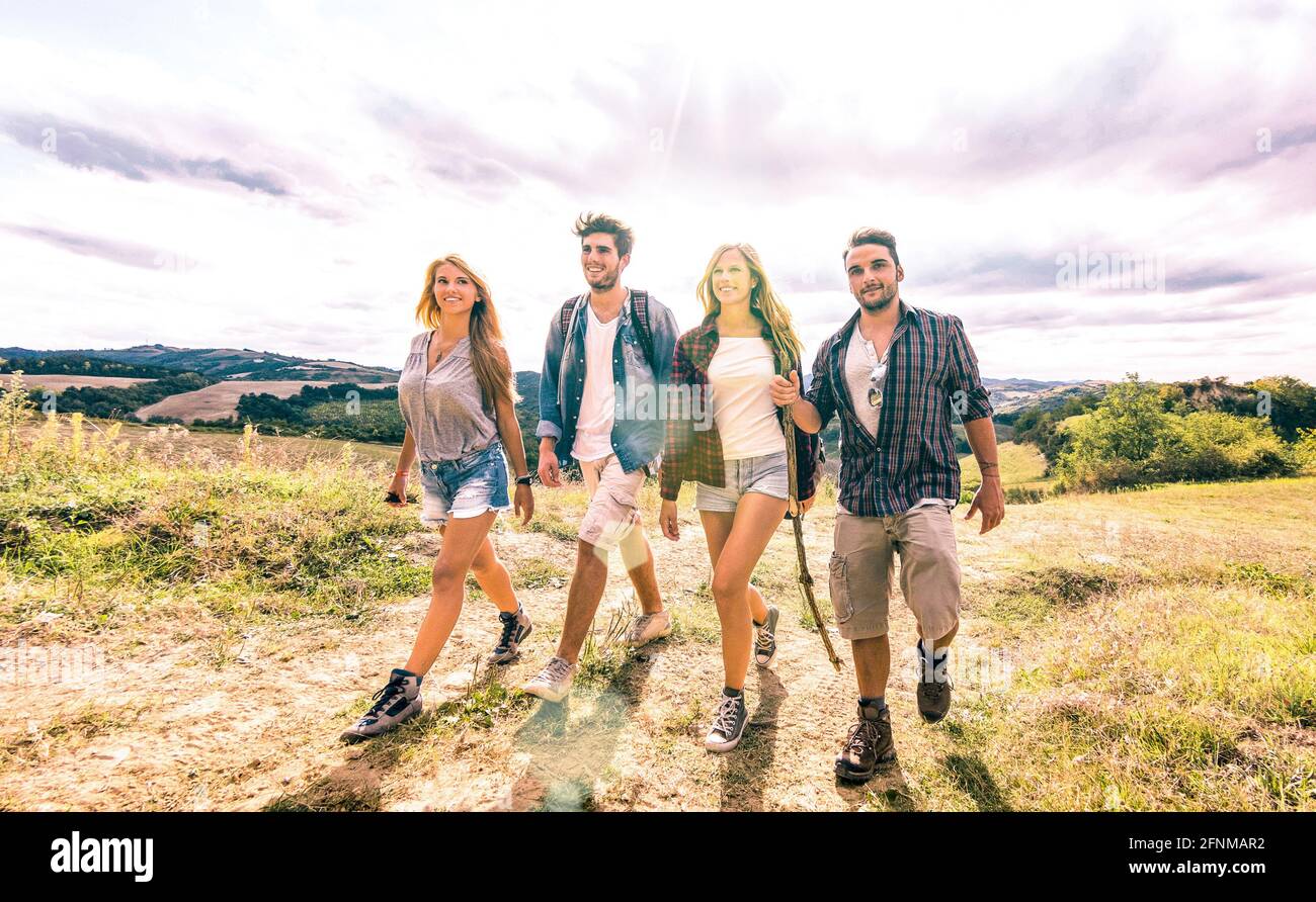 Best friends group walking free on grass meadow - Friendship and freedom concept with young millenial people sharing camping experience Stock Photo