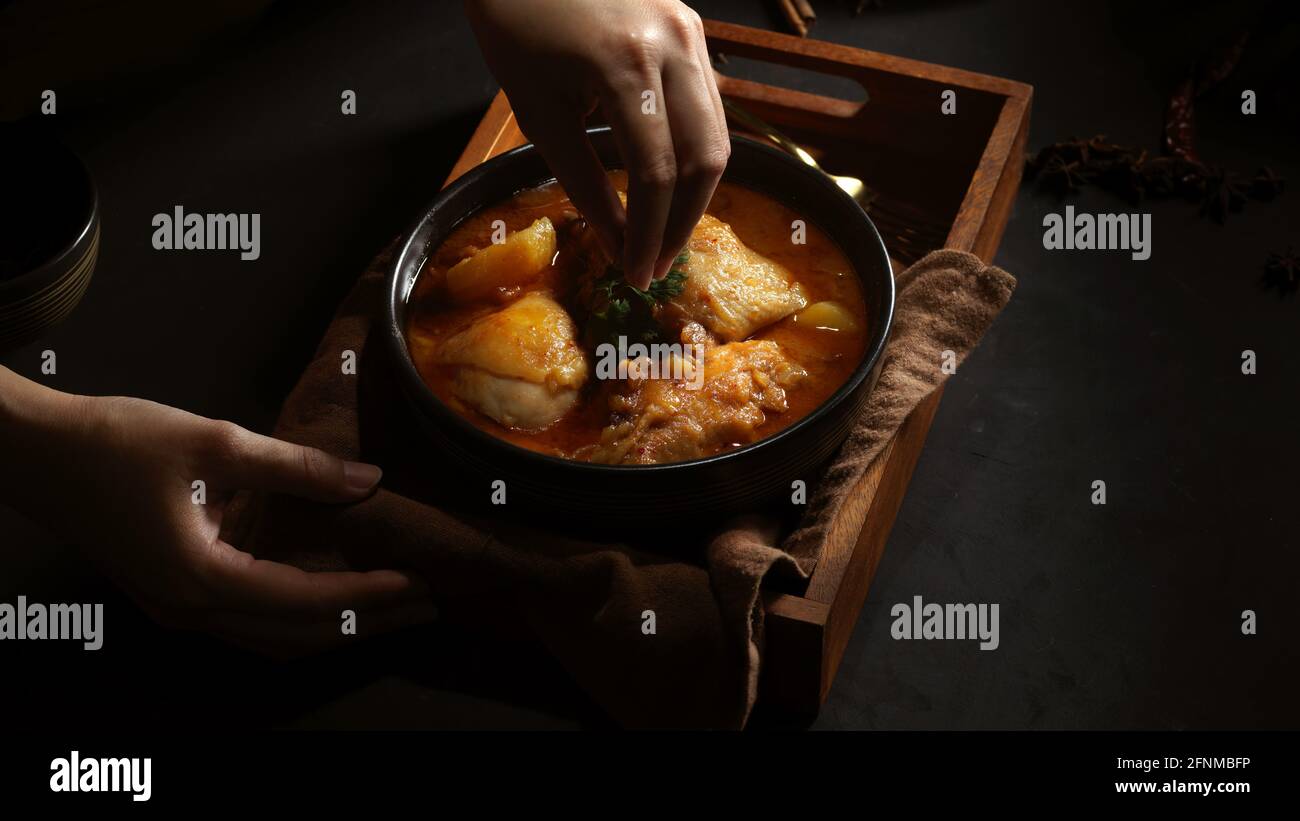 Cropped shot of female hand cooking chicken Massaman Curry to serve in Thai restaurant Stock Photo