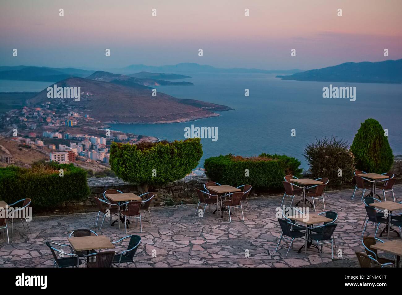 Street café with stunning view – seascape, hills, mountains and islands. Albanian resort Ksamil at sunset. Beautiful landscape. Stock Photo