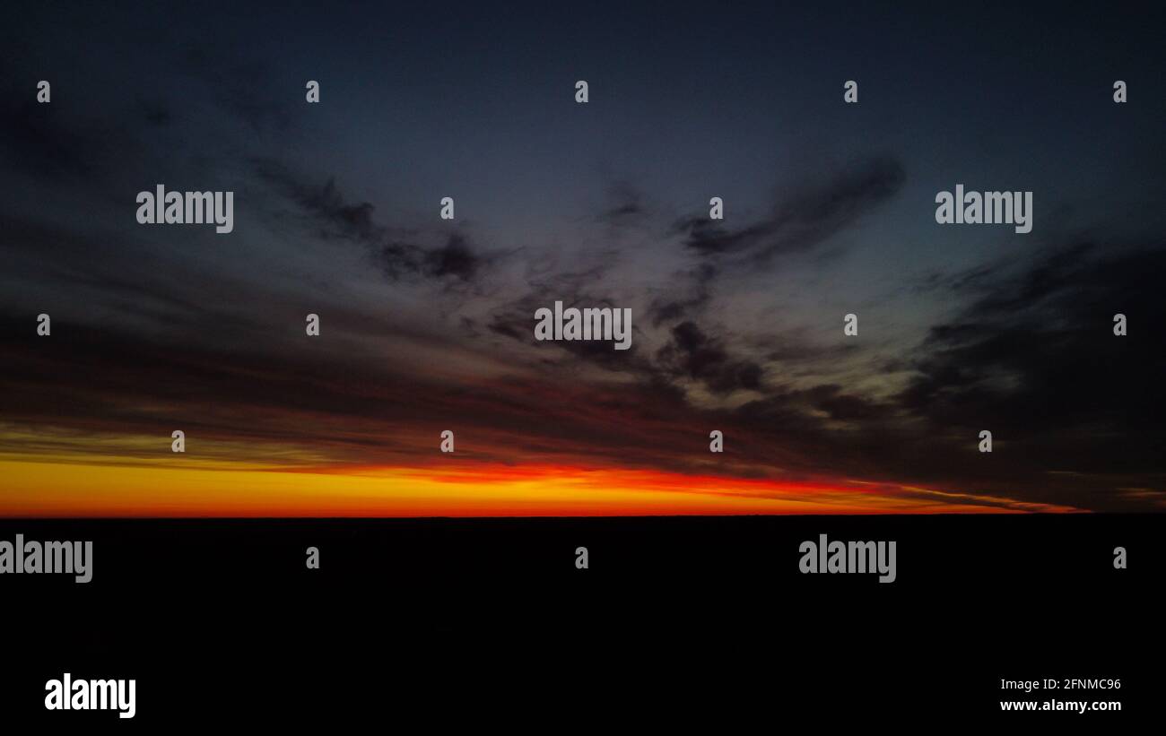 Beautiful orange and red sunset view with cumulus rain clouds from the drone view. Aerial landscape. Stock Photo