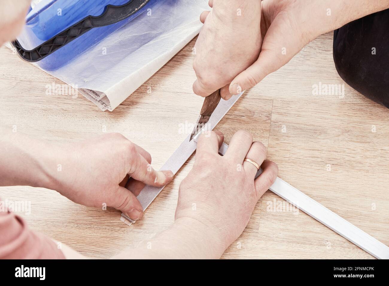 Skilled workers cut a wooden molding on the floor during wardrobe installation in light room extreme close view Stock Photo