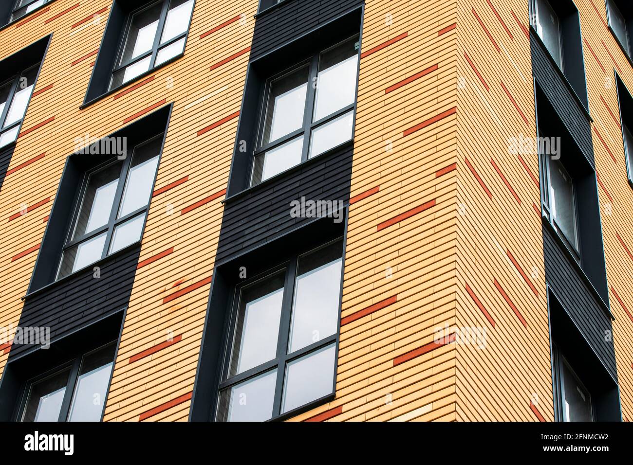 The wall of a brick multistoried building with transparent windows. Geometric abstract pattern. House facade texture, background Stock Photo