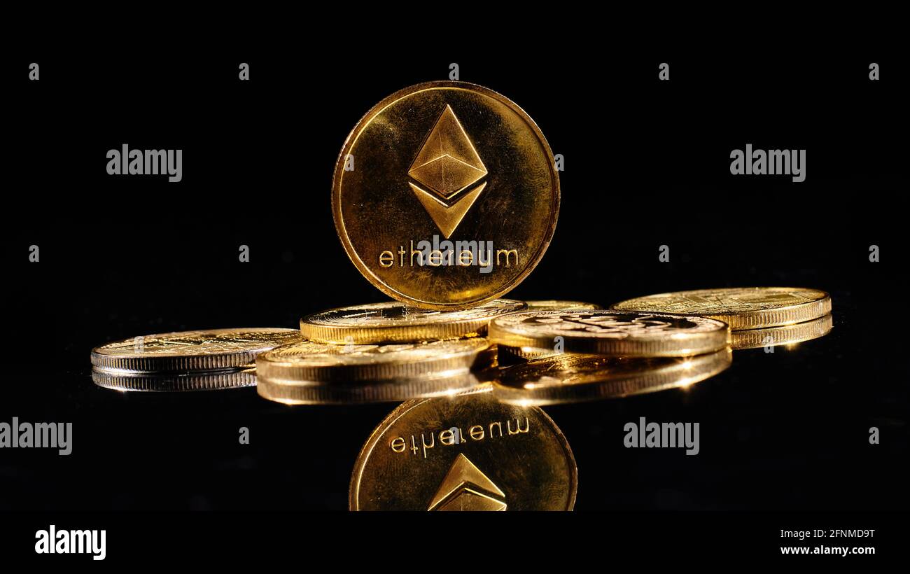 Closeup golden coin with Ether logo. New cryptocurrency Ethereum ETH 2.0 on a top of bitcoin coins against black background. A heap of decentralized Stock Photo