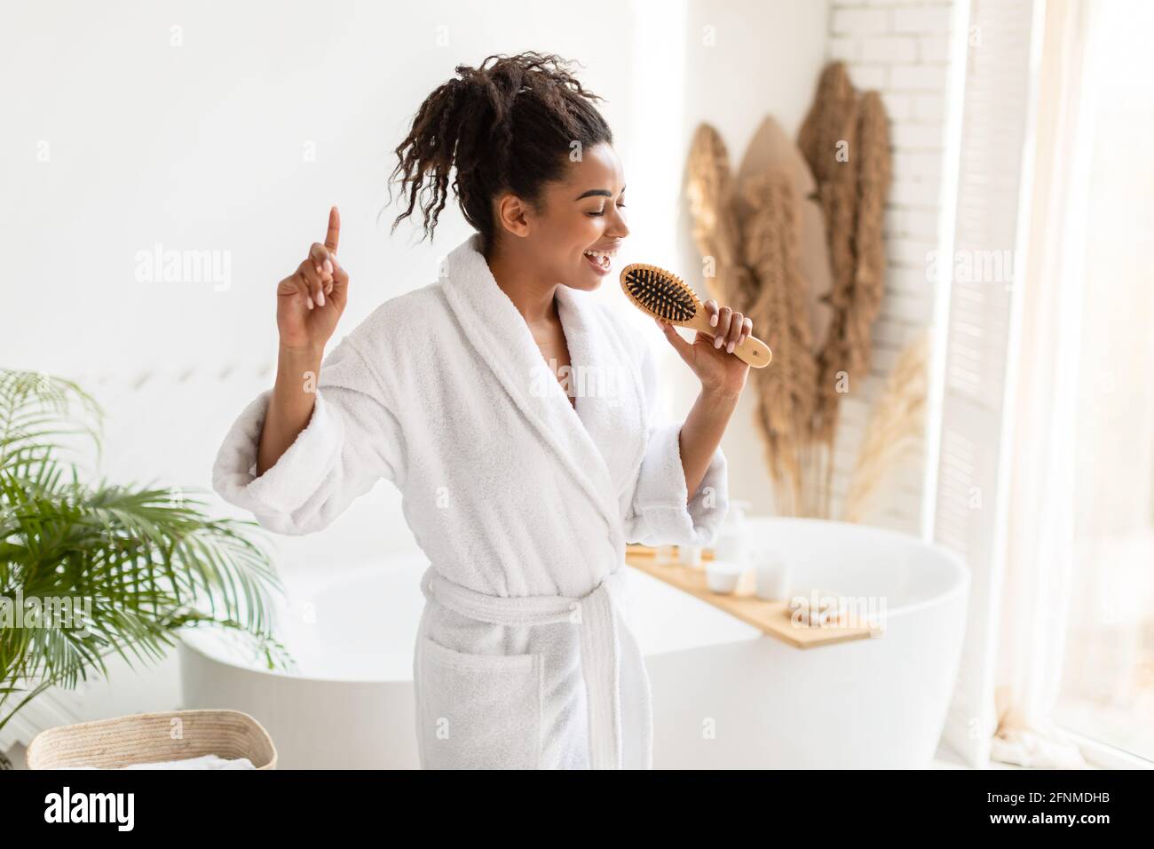 Cheerful African American Lady Singing With Hairbrush In Modern Bathroom Stock Photo