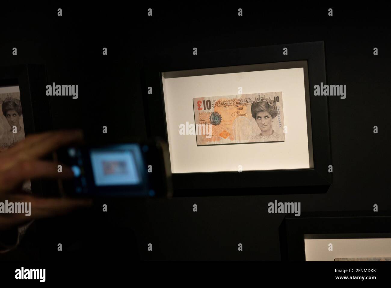 A person takes a photo of a Di-Faced Tenner at The Art of Banksy exhibition at 50 Earlham Street, London. Picture date: Tuesday May 18, 2021. Stock Photo