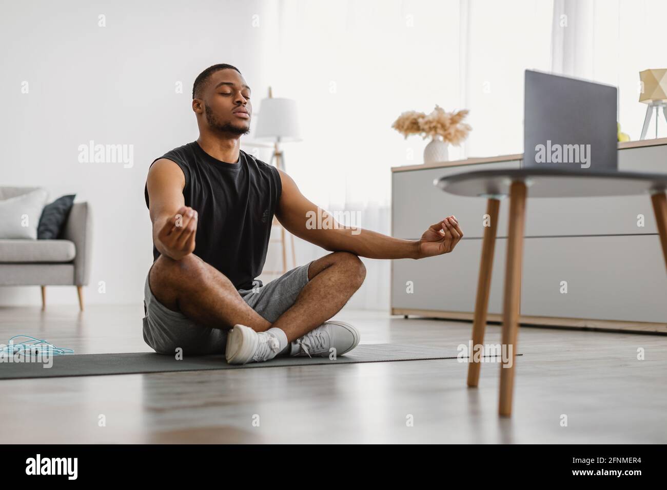 Peaceful African American Guy Meditating At Computer At Home Stock Photo