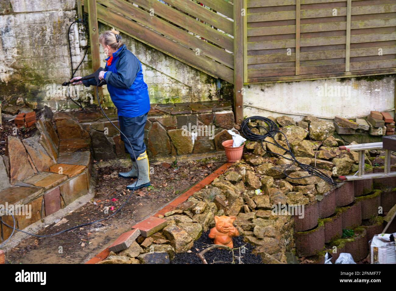Worker cleaning driveway with gasoline high pressure washer splashing