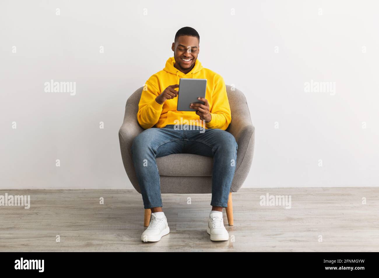 Happy Black Guy Using Digital Tablet Browsing Internet, Gray Background Stock Photo