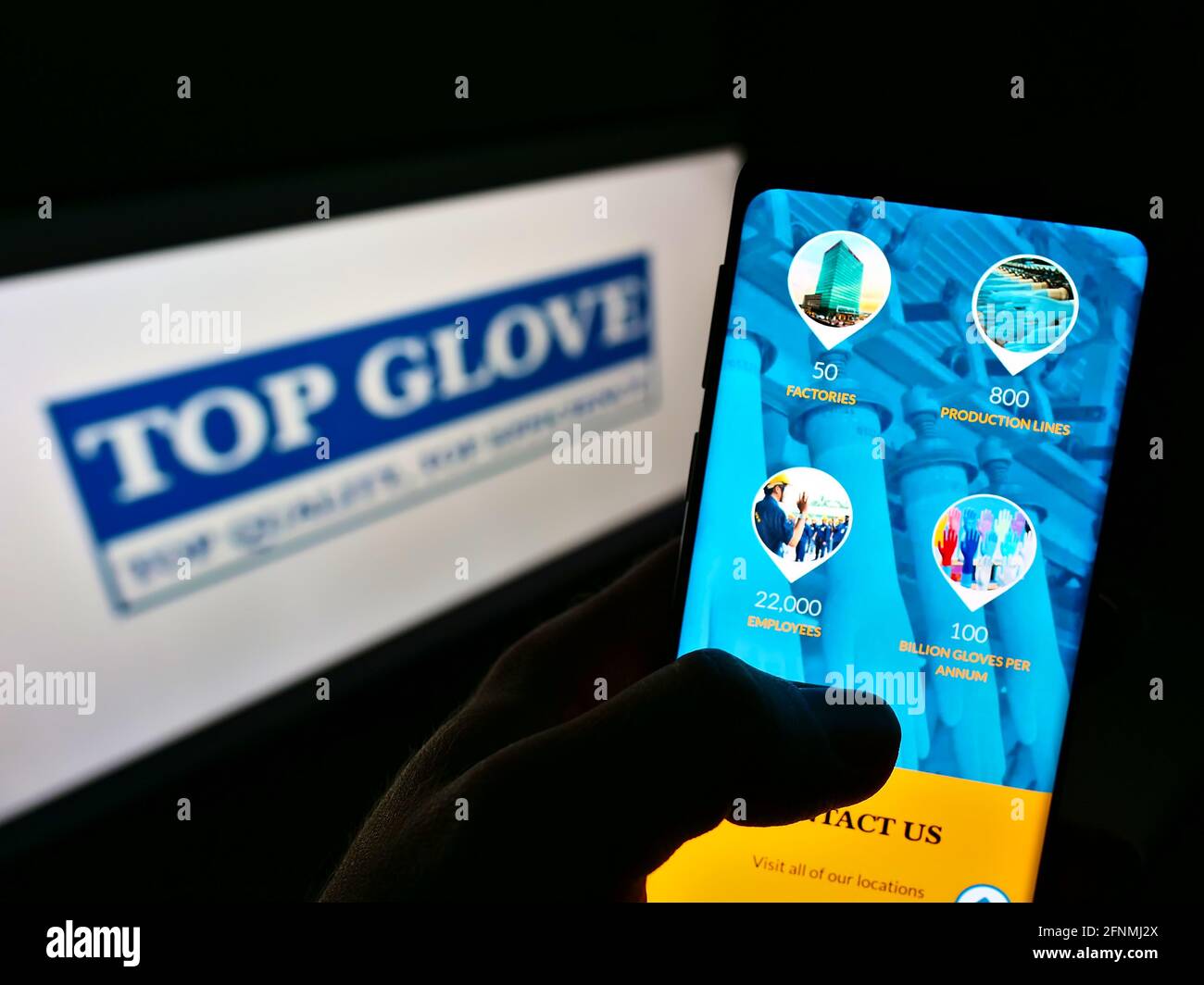 Person holding smartphone with webpage of Malaysian company Top Glove