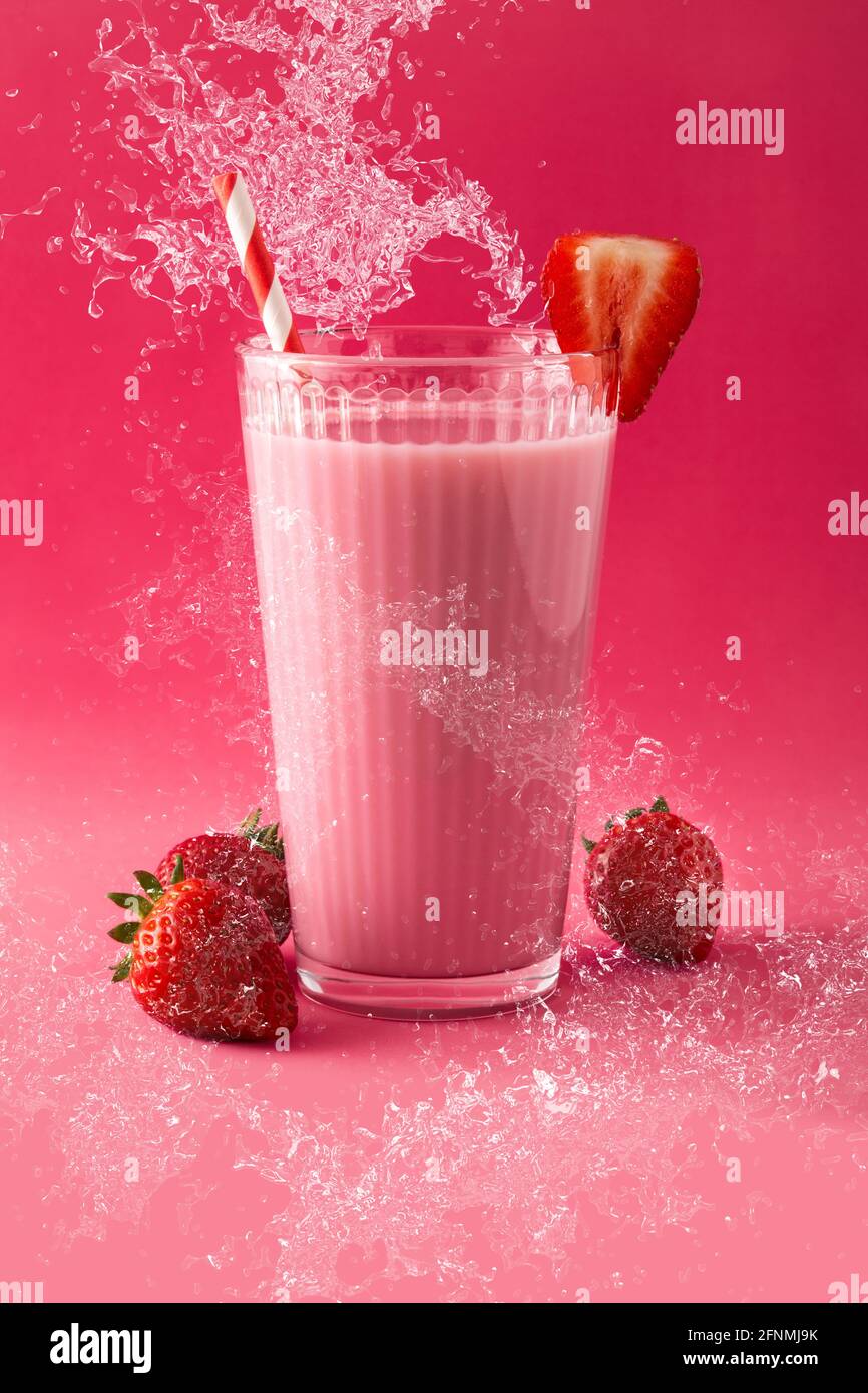 Strawberry milkshake splashing in glass on pink background Stock Photo Alamy