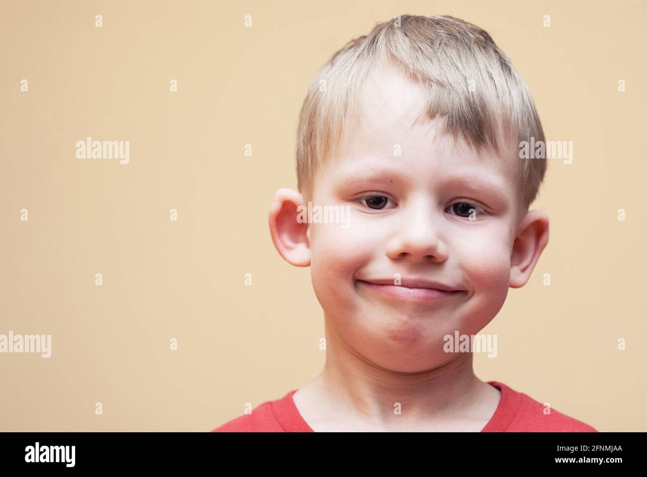 Portrait of smiling boy with brown eyes in red outfit posing for camera