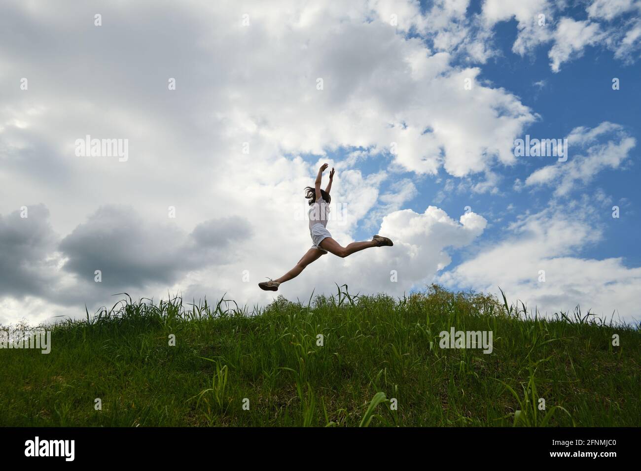 Happy girl jumping against the background of blue sky and clouds Stock ...